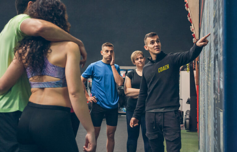 Séance de briefing en salle de sport dans le cadre de la formation BPJEPS ATP : un formateur explique un programme à un groupe de stagiaires en tenue sportive.