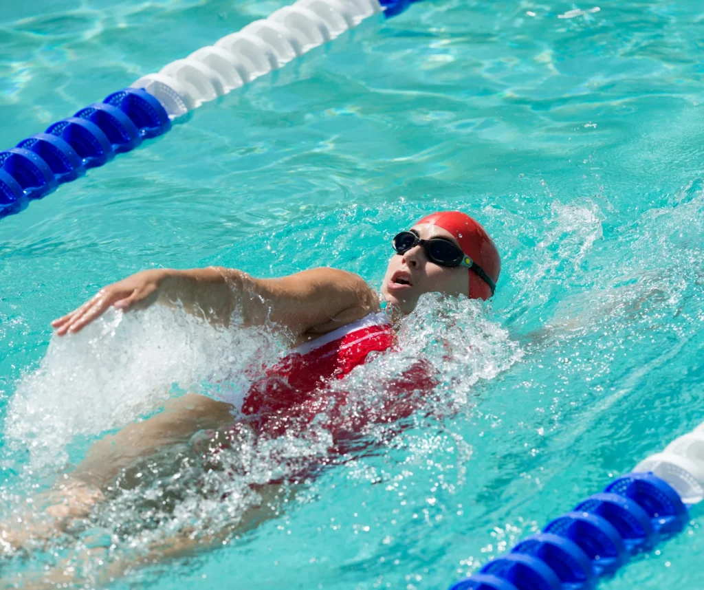 Future éducatrice aquatique en formation BPJEPS AAN, souriante dans un bassin, ajustant son bonnet de bain avant une séance de natation.